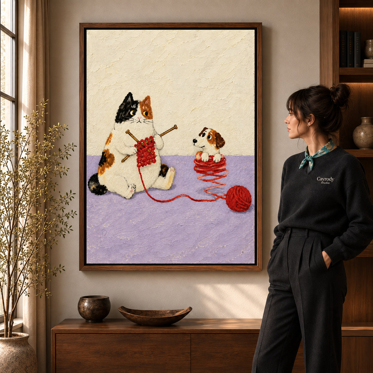 Walnut framed knitting cat canvas art shown beside a standing woman and a wooden console.