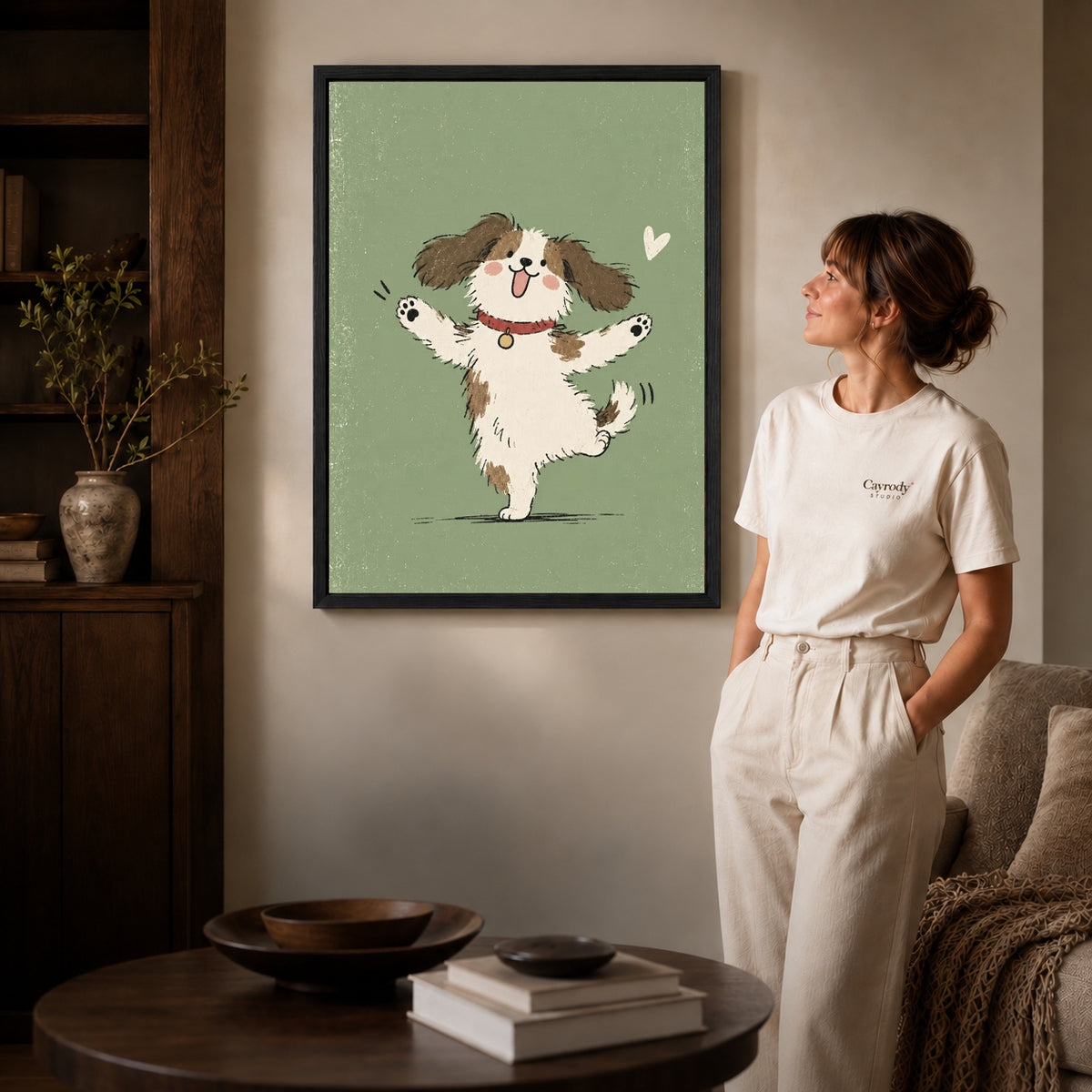 Dancing puppy canvas art in a black frame above stacked books in a cozy living room.