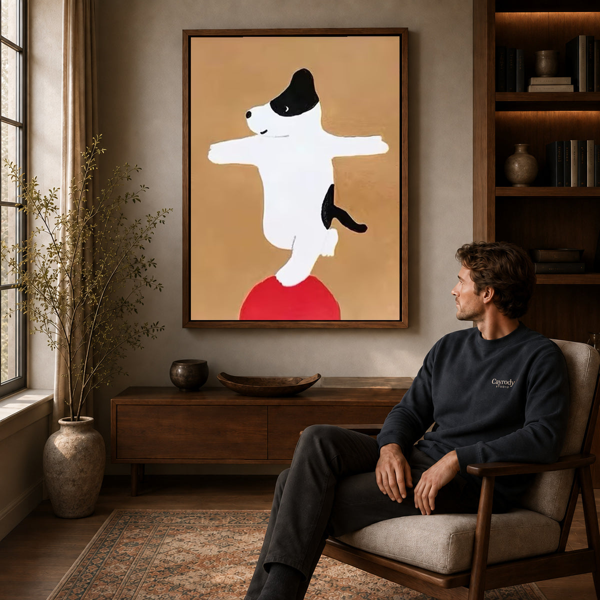 Balancing dog canvas art above a wooden console near a seated man and leafy branches.