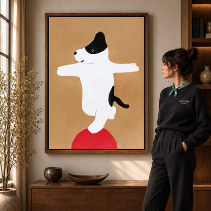 Balancing dog canvas art displayed in a walnut frame against a warm wall near a wooden console.