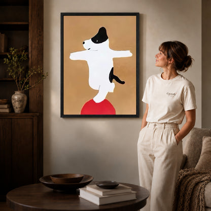 Balancing dog canvas art displayed in a black frame beside a woman, with soft room lighting.