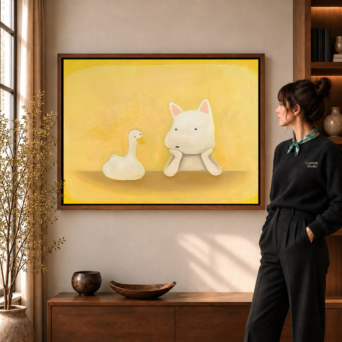 Dog and duck canvas art in a walnut frame beside a woman in a warmly lit living room.