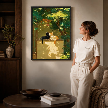 Garden cats canvas art in a black frame above stacked books in a cozy living room.