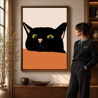 Black cat canvas art in a walnut frame beside a woman in a warmly lit living room.