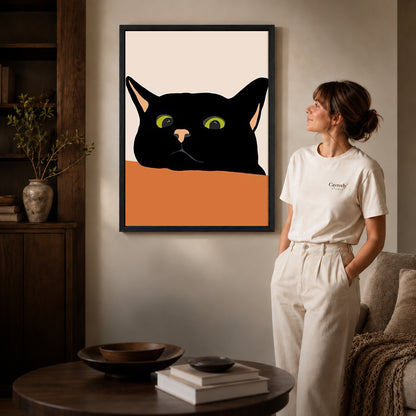 Black cat canvas art in a black frame above stacked books in a cozy living room.
