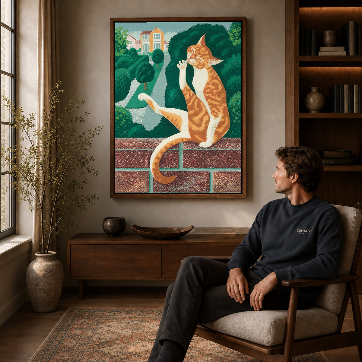 Garden tabby canvas art above a wooden console near a seated man and leafy branches.