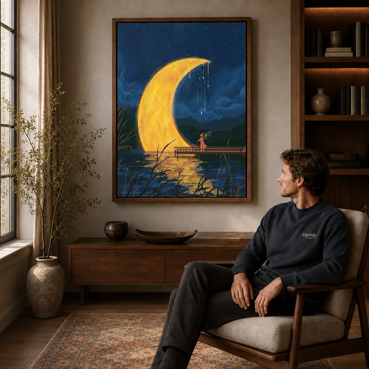 Crescent moon canvas art above a wooden console near a seated man and leafy branches.