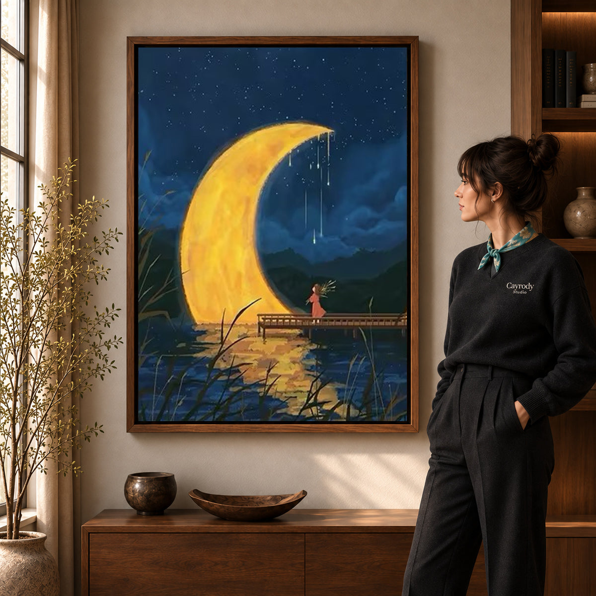 Crescent moon canvas art displayed in a walnut frame against a warm wall near a wooden console.