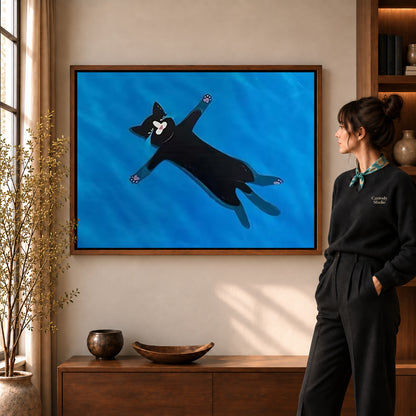 Floating black cat canvas art in a walnut frame beside a woman in a warmly lit living room.