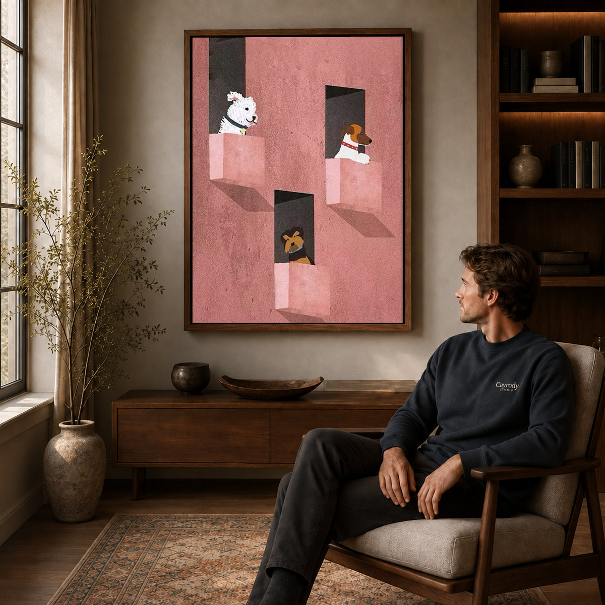 Window dogs canvas art above a wooden console near a seated man and leafy branches.