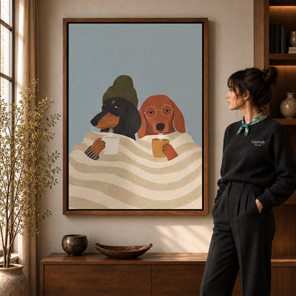 Cozy Coffee Dogs canvas art in a walnut frame beside a standing woman and wooden console.