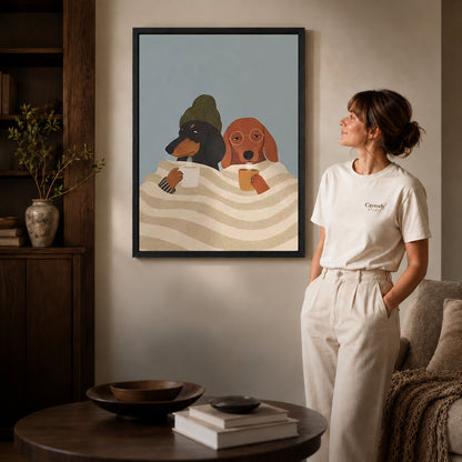 Black framed cozy coffee dogs canvas art displayed beside a woman in a warm living room.