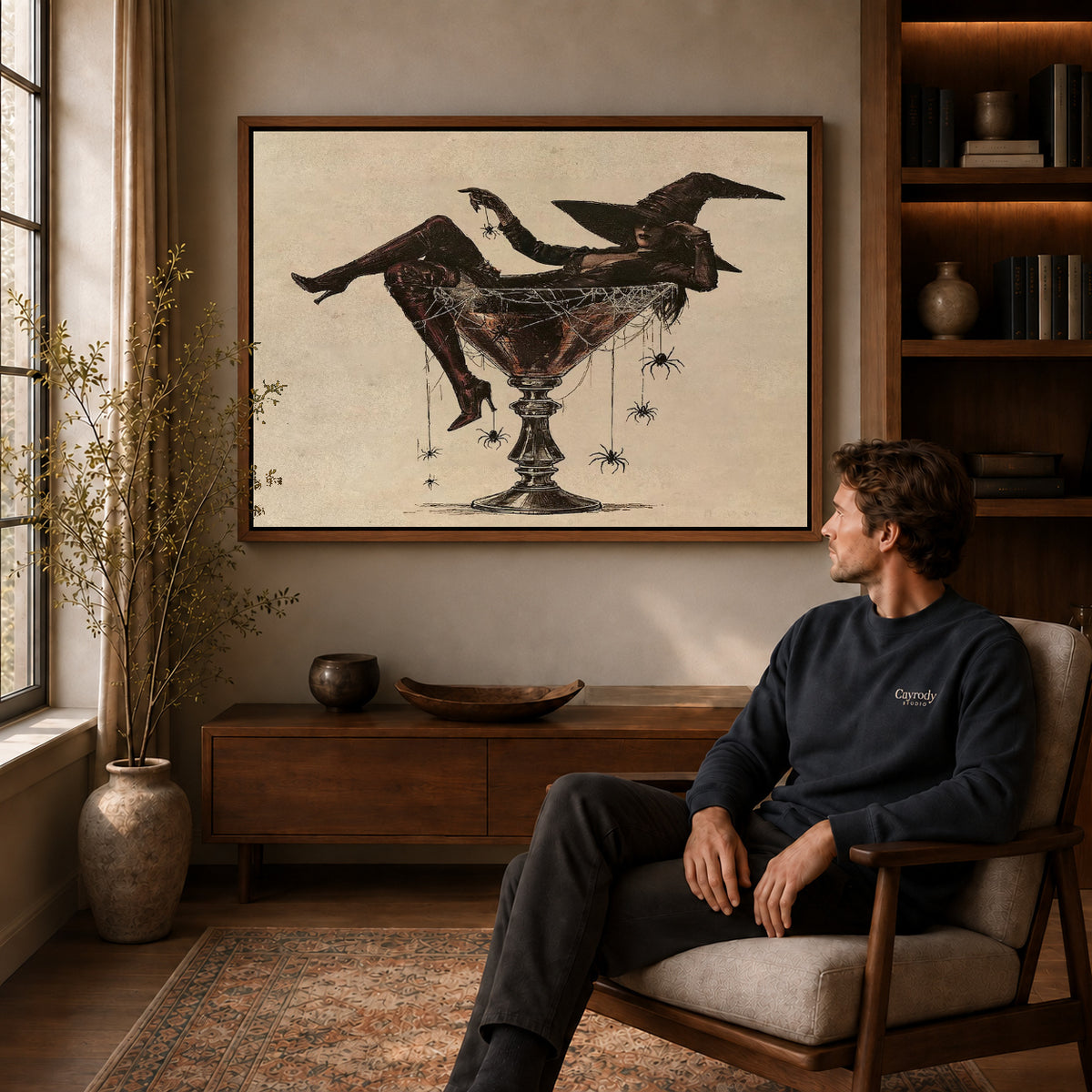 Martini Witch canvas art above a wooden console beside a seated man in a warm room.