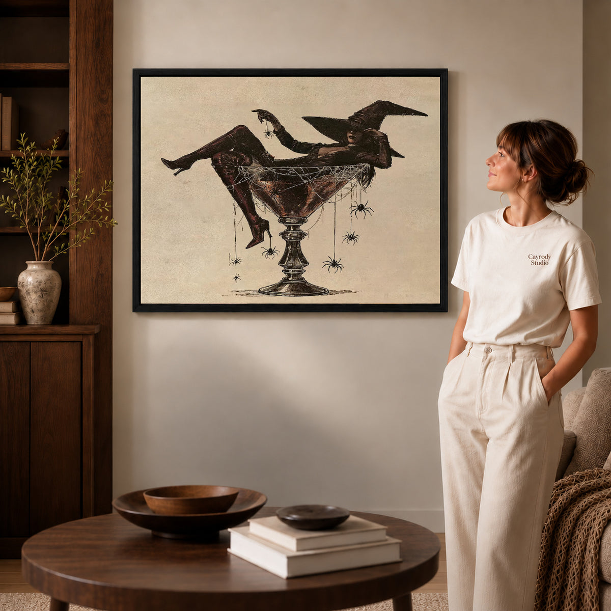 Martini Witch canvas art in a black frame above books in a welcoming living room.