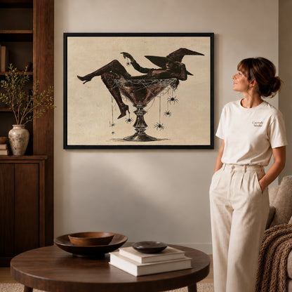 Black framed martini witch canvas art displayed beside a woman in a warm living room.
