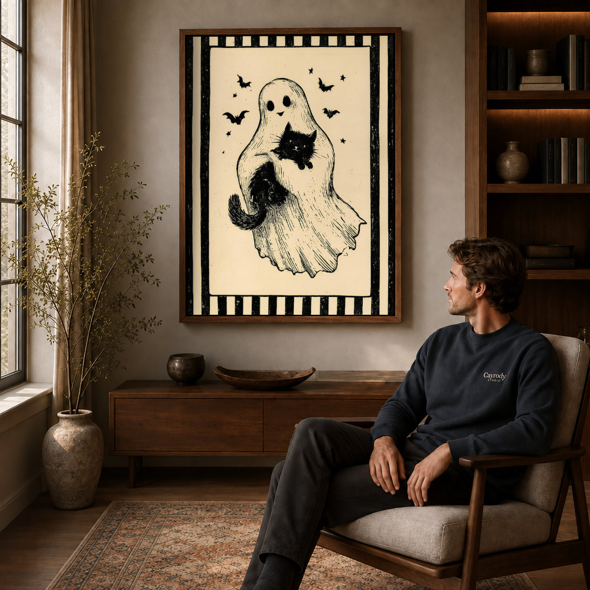 Ghost And Cat canvas art above a wooden console beside a seated man in a warm room.