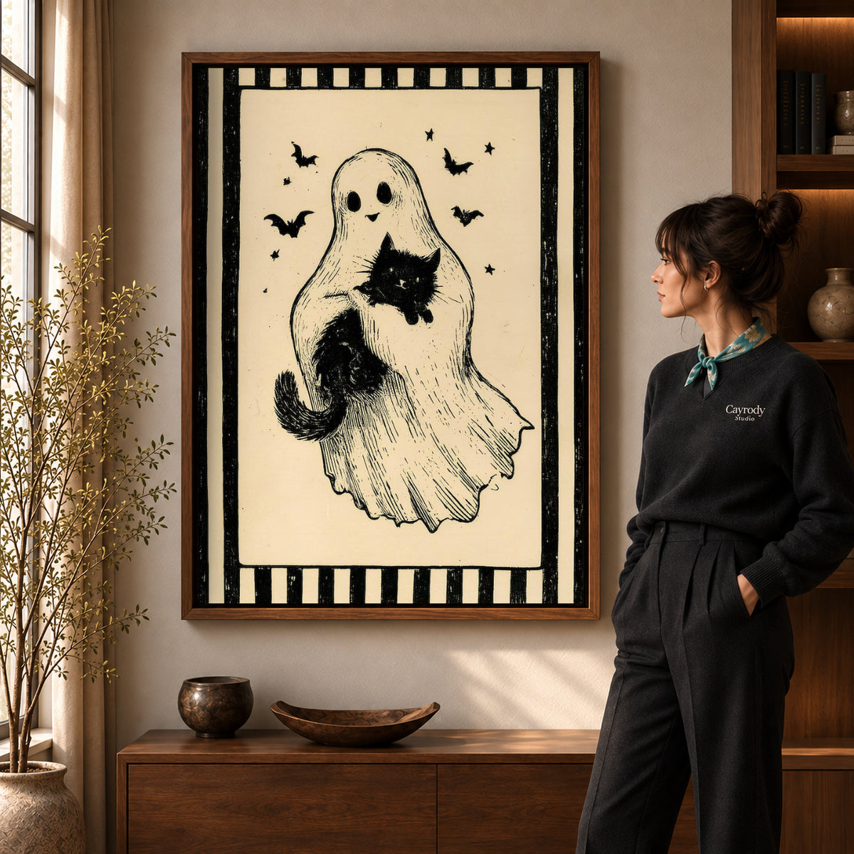 Walnut framed ghost and cat canvas art shown beside a standing woman and a wooden console.