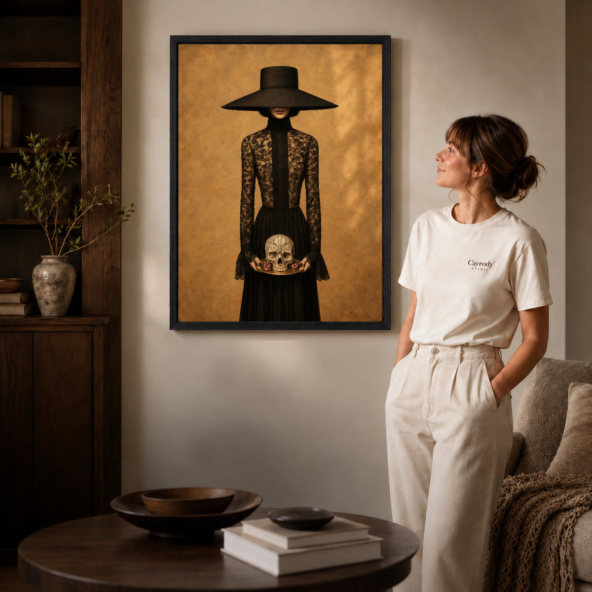 Black framed gothic lady canvas art displayed beside a woman in a warm living room.