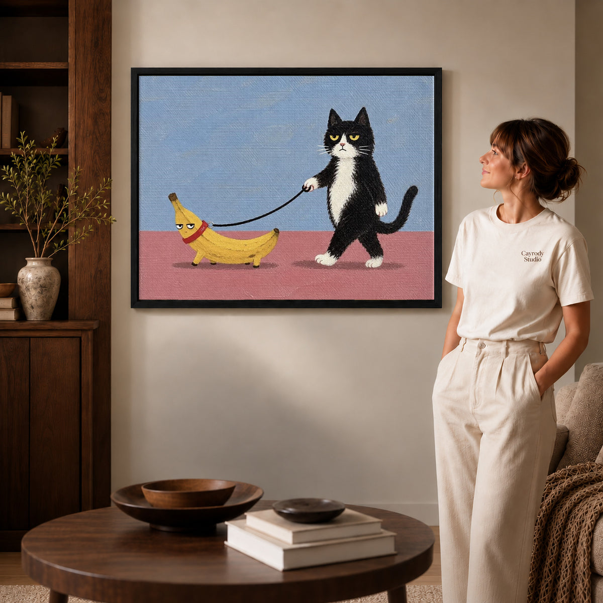 Banana Walk canvas art in a black frame above books in a welcoming living room.