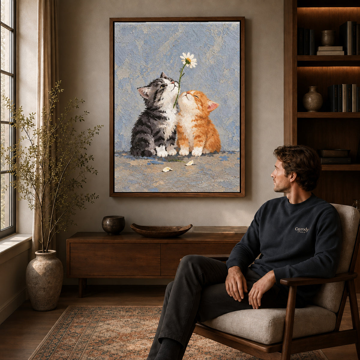 Daisy Kittens canvas art above a wooden console beside a seated man in a warm room.