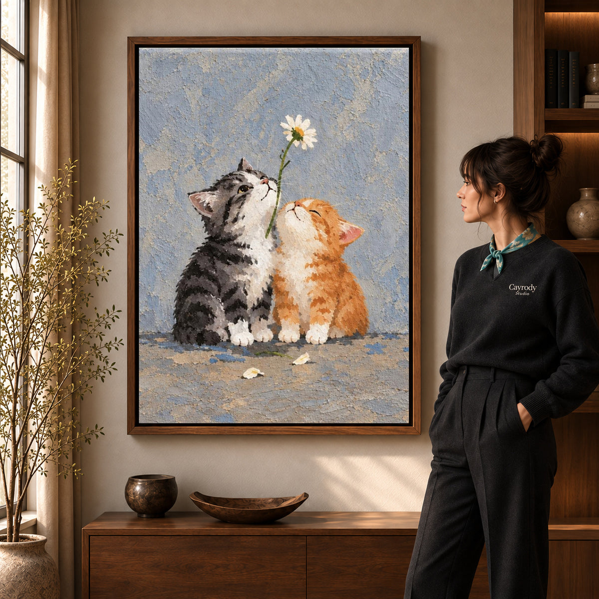 Walnut framed daisy kittens canvas art shown beside a standing woman and a wooden console.