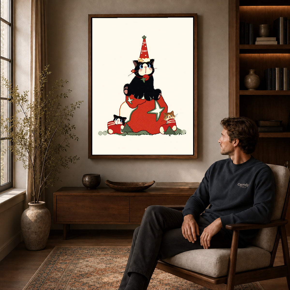 Christmas Kittens canvas art above a wooden console beside a seated man in a warm room.