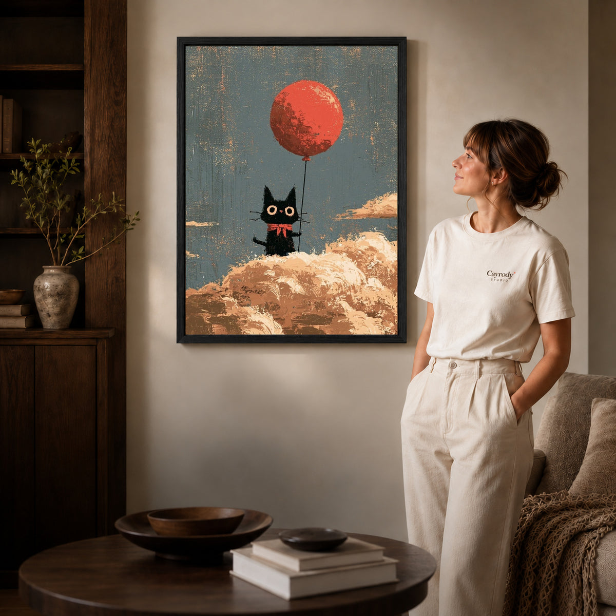 Black framed cloud cat canvas art displayed beside a woman in a warm living room.