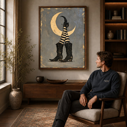 Moonlit Witch Boots canvas art above a wooden console beside a seated man in a warm room.