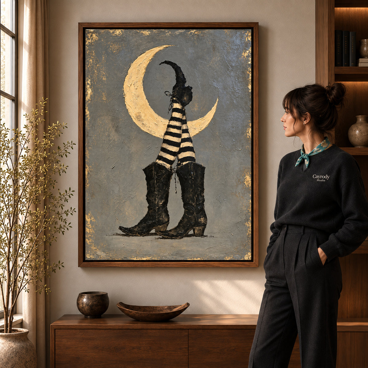 Walnut framed moonlit witch boots canvas art shown beside a standing woman and a wooden console.