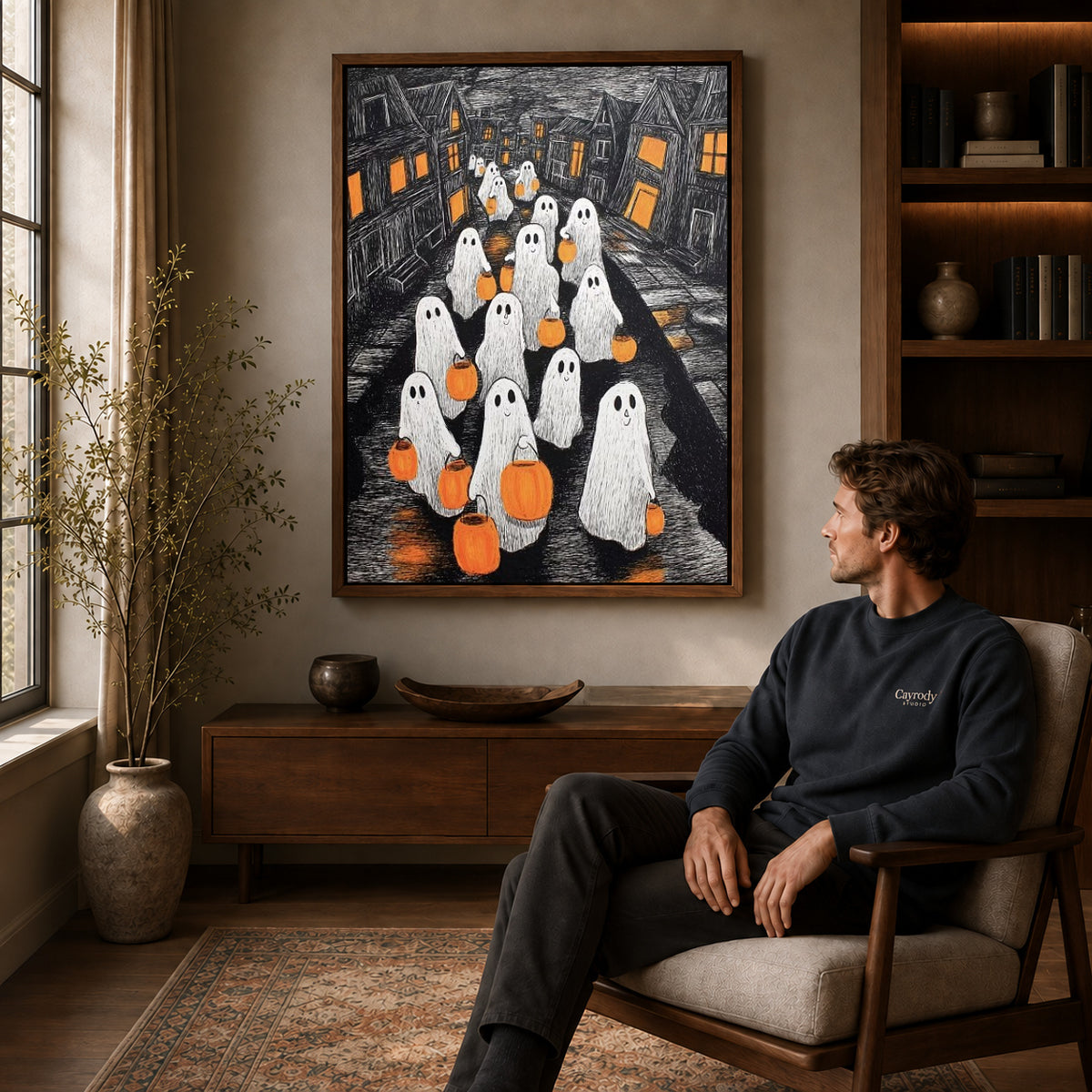 Pumpkin Ghosts canvas art above a wooden console beside a seated man in a warm room.