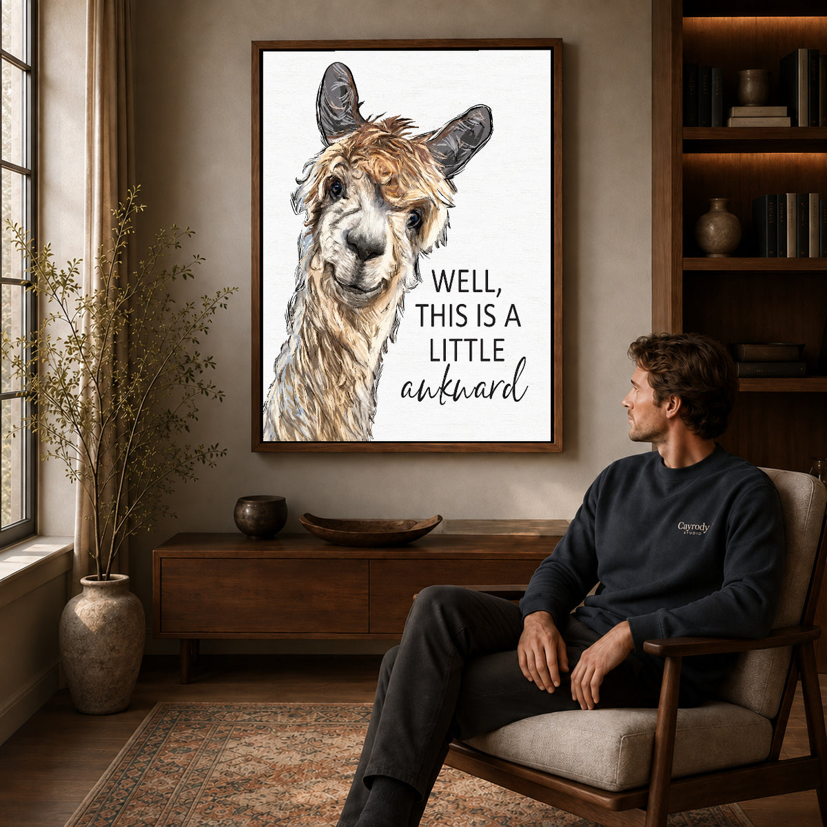 Awkward Alpaca canvas art above a wooden console beside a seated man in a warm room.