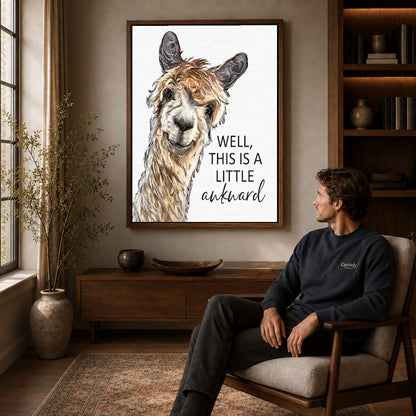 Awkward Alpaca canvas art above a wooden console beside a seated man in a warm room.