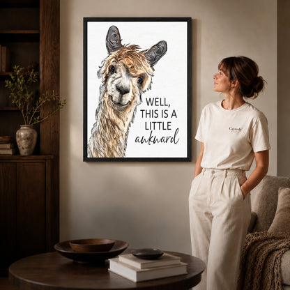 Awkward Alpaca canvas art in a black frame above books in a welcoming living room.