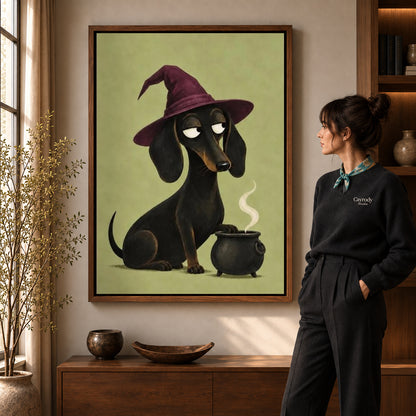 Dachshund Witch canvas art in a walnut frame beside a standing woman and wooden console.