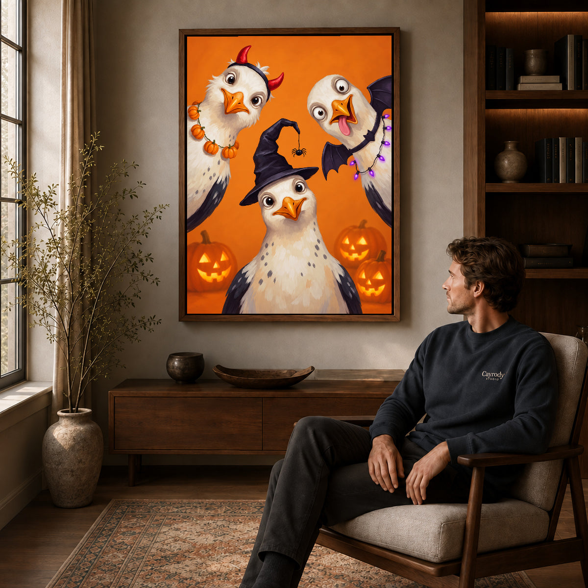 Halloween Bird Trio canvas art above a wooden console beside a seated man in a warm room.