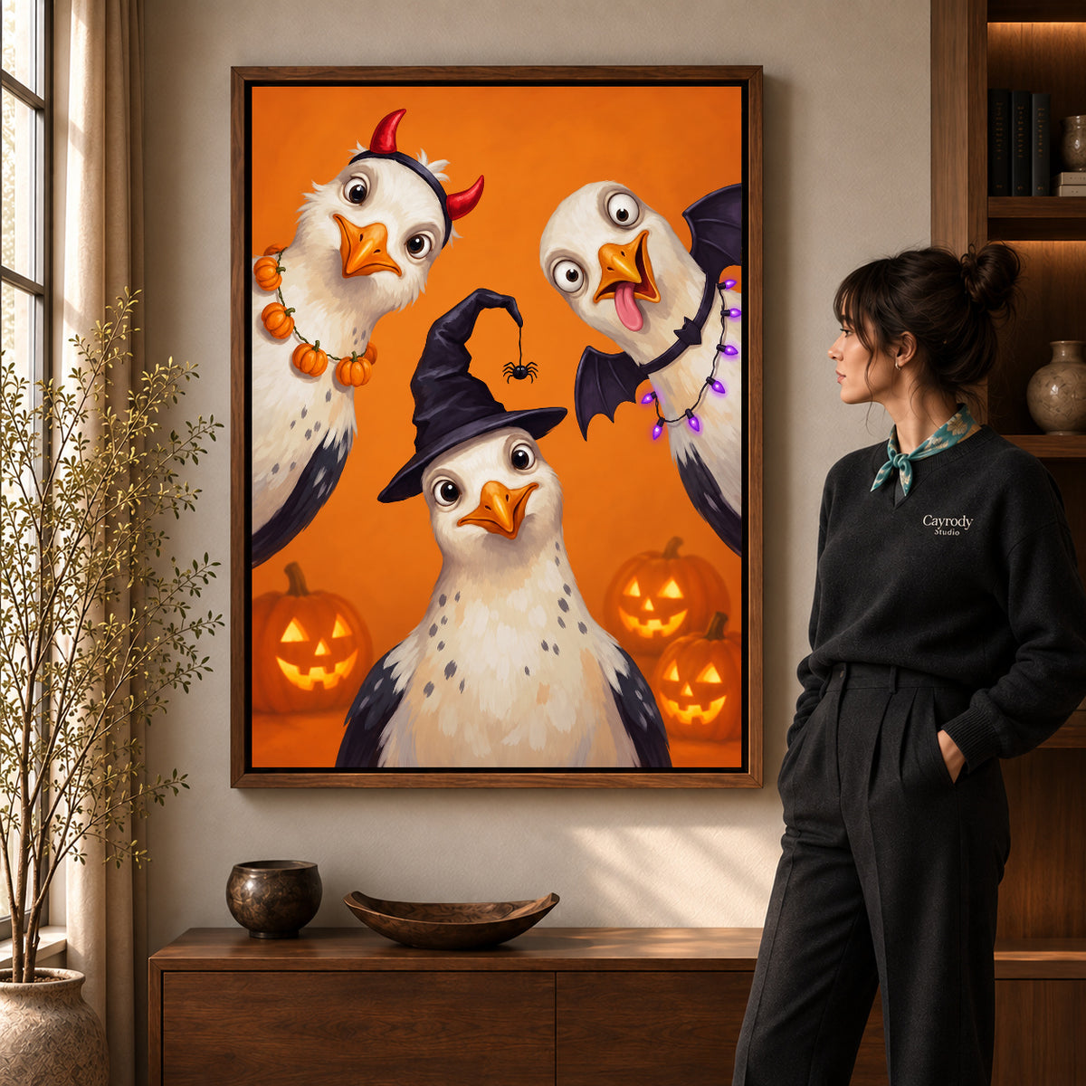 Walnut framed halloween bird trio canvas art shown beside a standing woman and a wooden console.