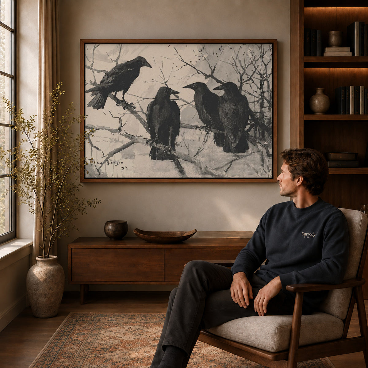 Four Ravens canvas art above a wooden console beside a seated man in a warm room.