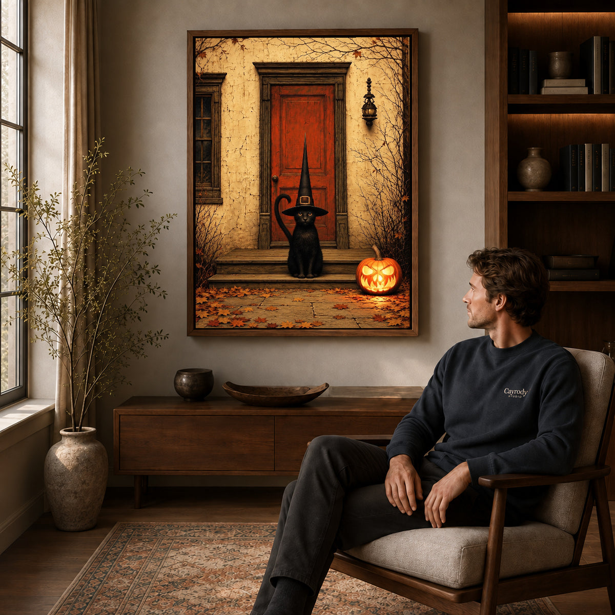 Porch Witch Cat canvas art above a wooden console beside a seated man in a warm room.