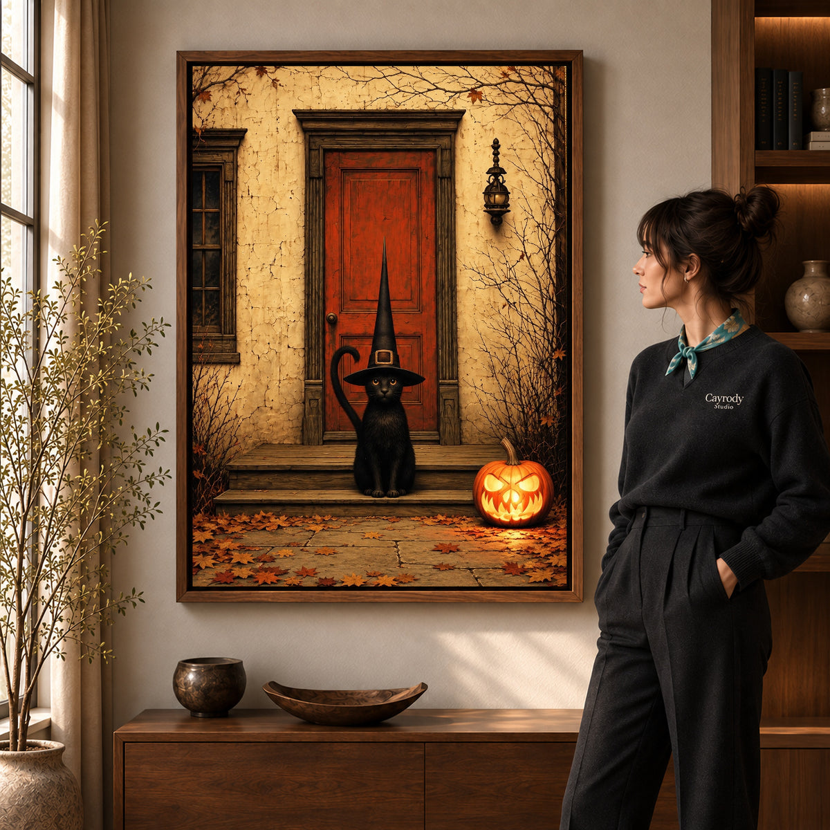 Walnut framed porch witch cat canvas art shown beside a standing woman and a wooden console.