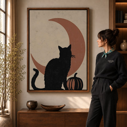 Black Cat Moon canvas art in a walnut frame beside a standing woman and wooden console.