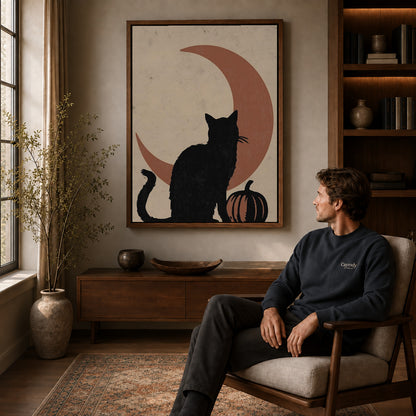 Black Cat Moon canvas art above a wooden console beside a seated man in a warm room.