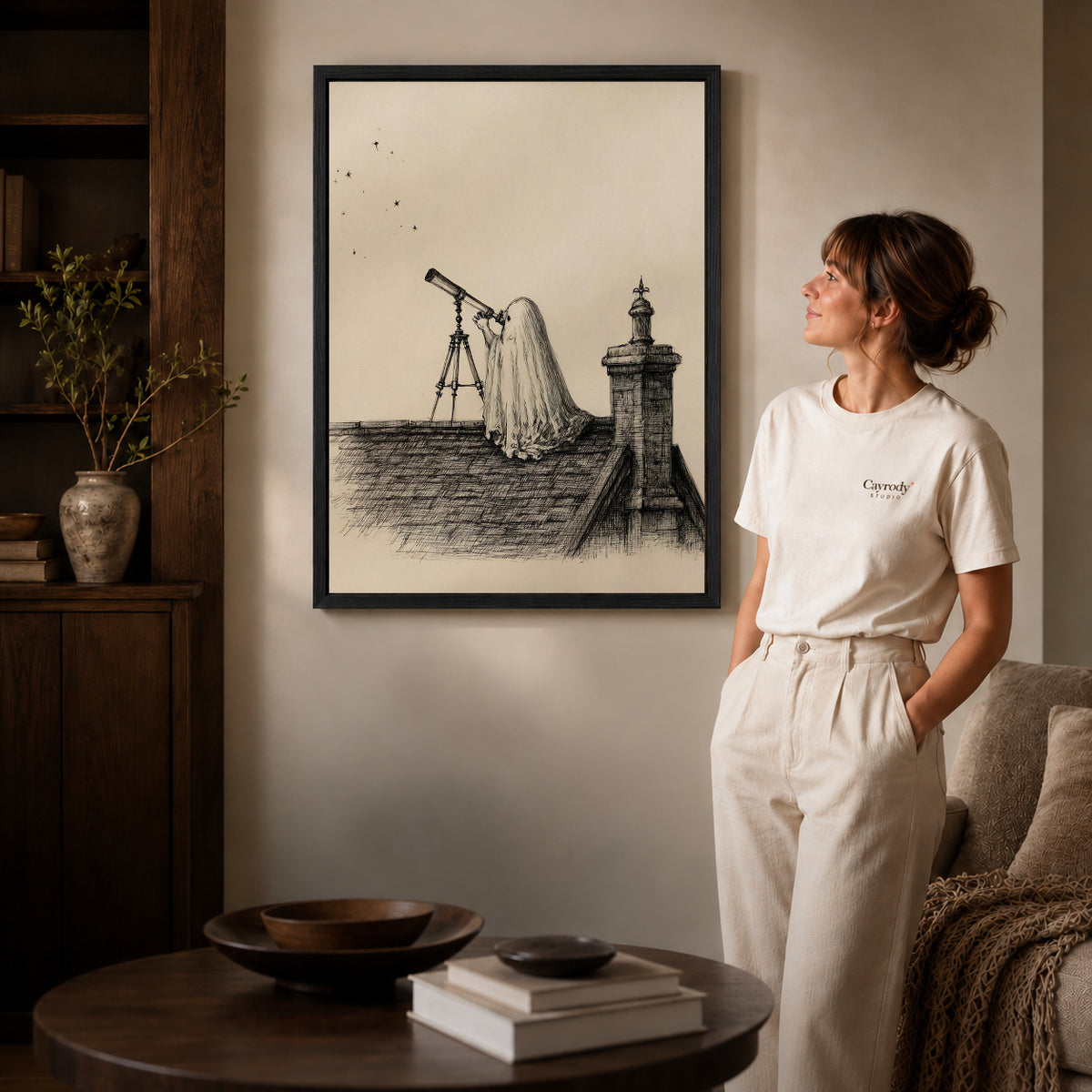 Stargazing Ghost canvas art in a black frame above books in a welcoming living room.