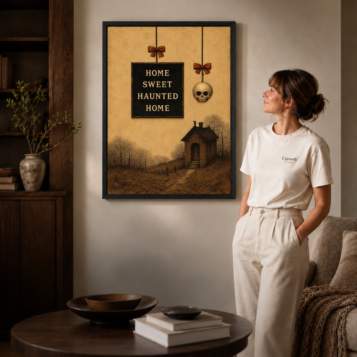 Haunted Home canvas art in a black frame above books in a welcoming living room.
