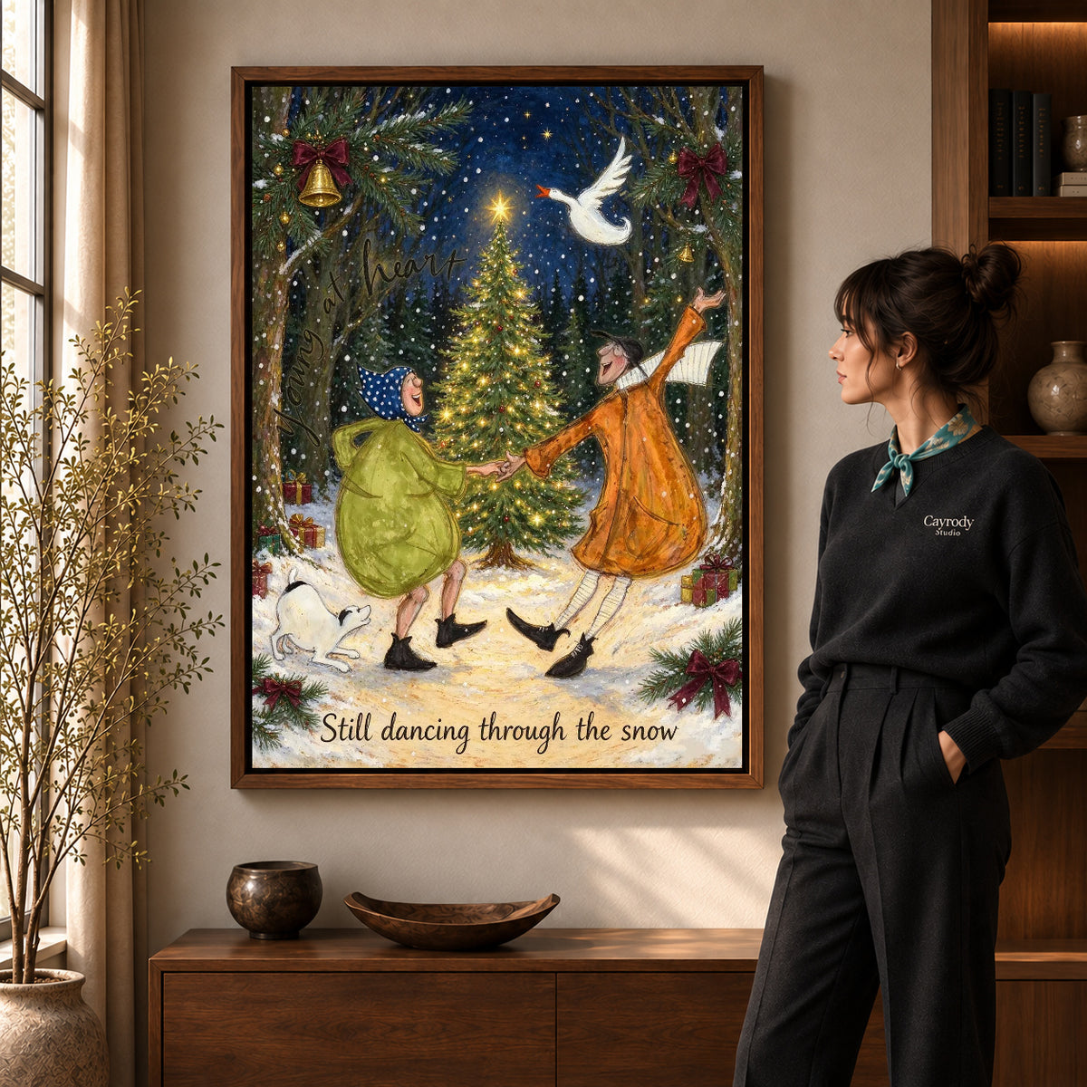 Snow Dance Couple canvas art in a walnut frame beside a standing woman and wooden console.