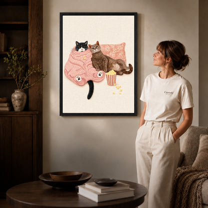 Black framed cozy movie cats canvas art displayed beside a woman in a warm living room.