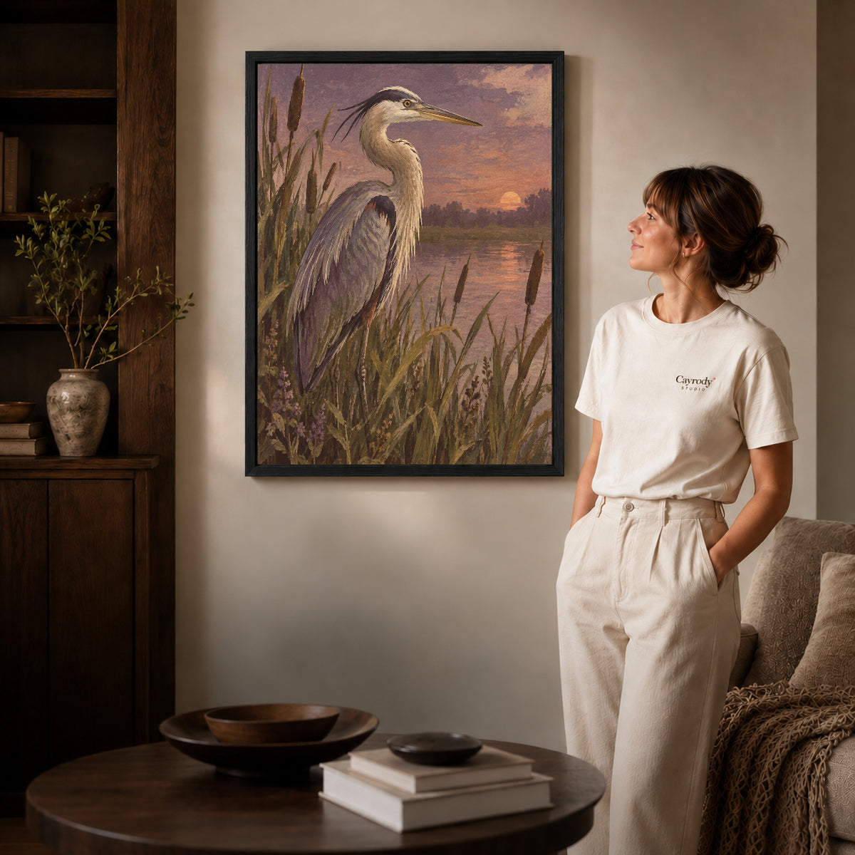 Marsh Heron canvas art in a black frame above books in a welcoming living room.