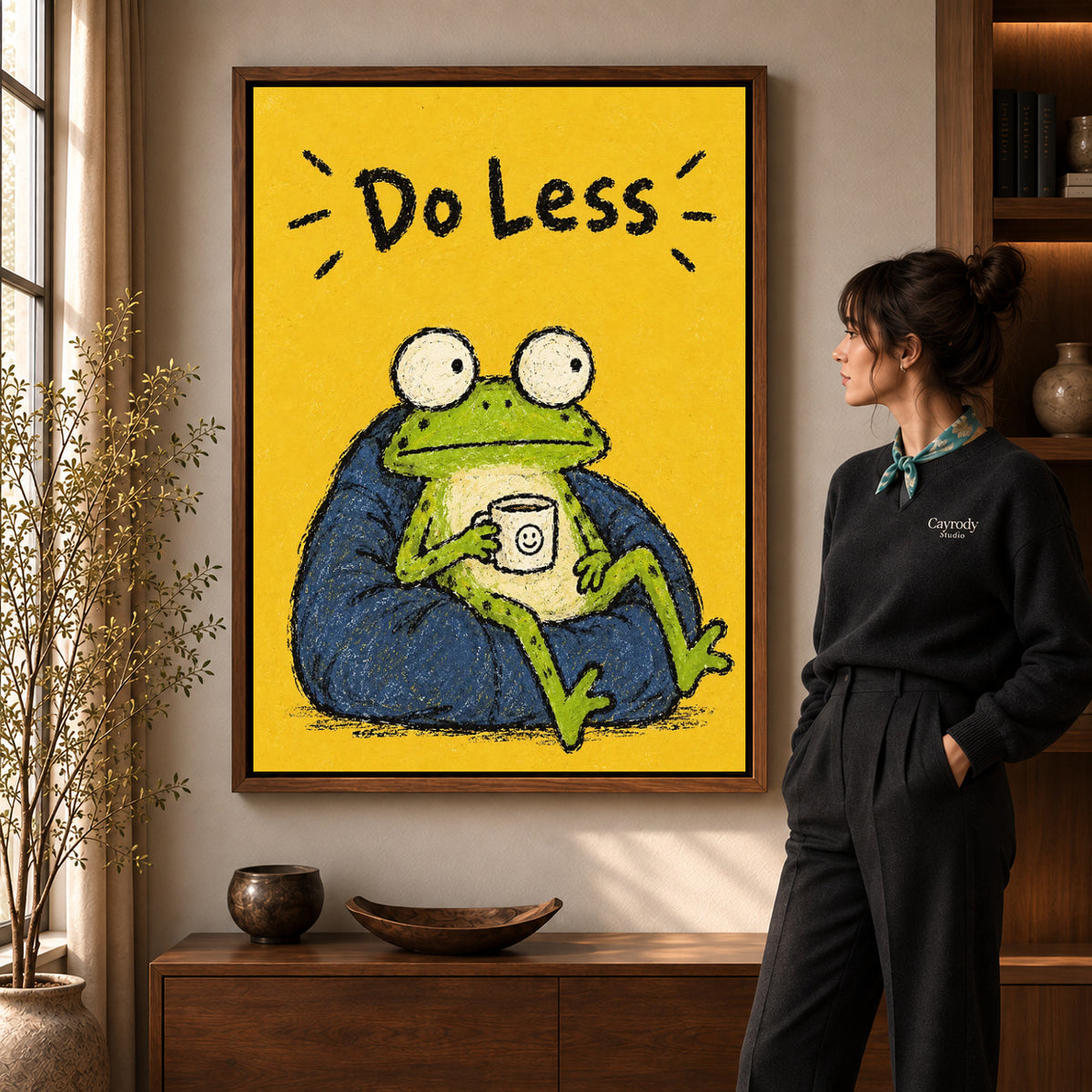 Resting Frog canvas art in a walnut frame beside a standing woman and wooden console.