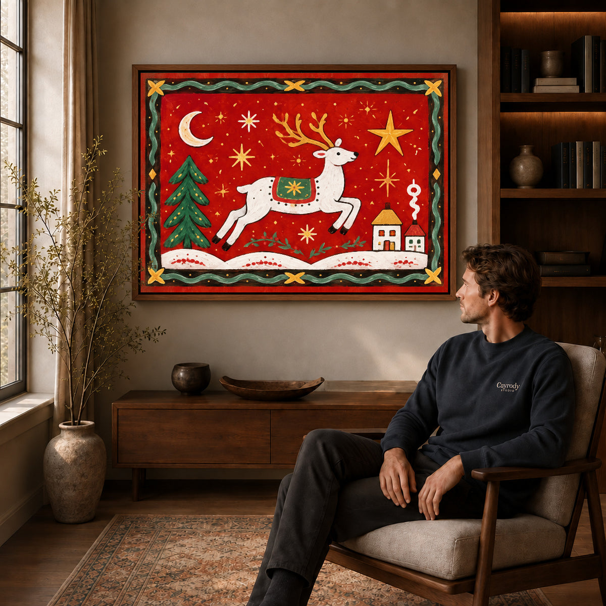 Festive Folk Reindeer canvas art above a wooden console beside a seated man in a warm room.