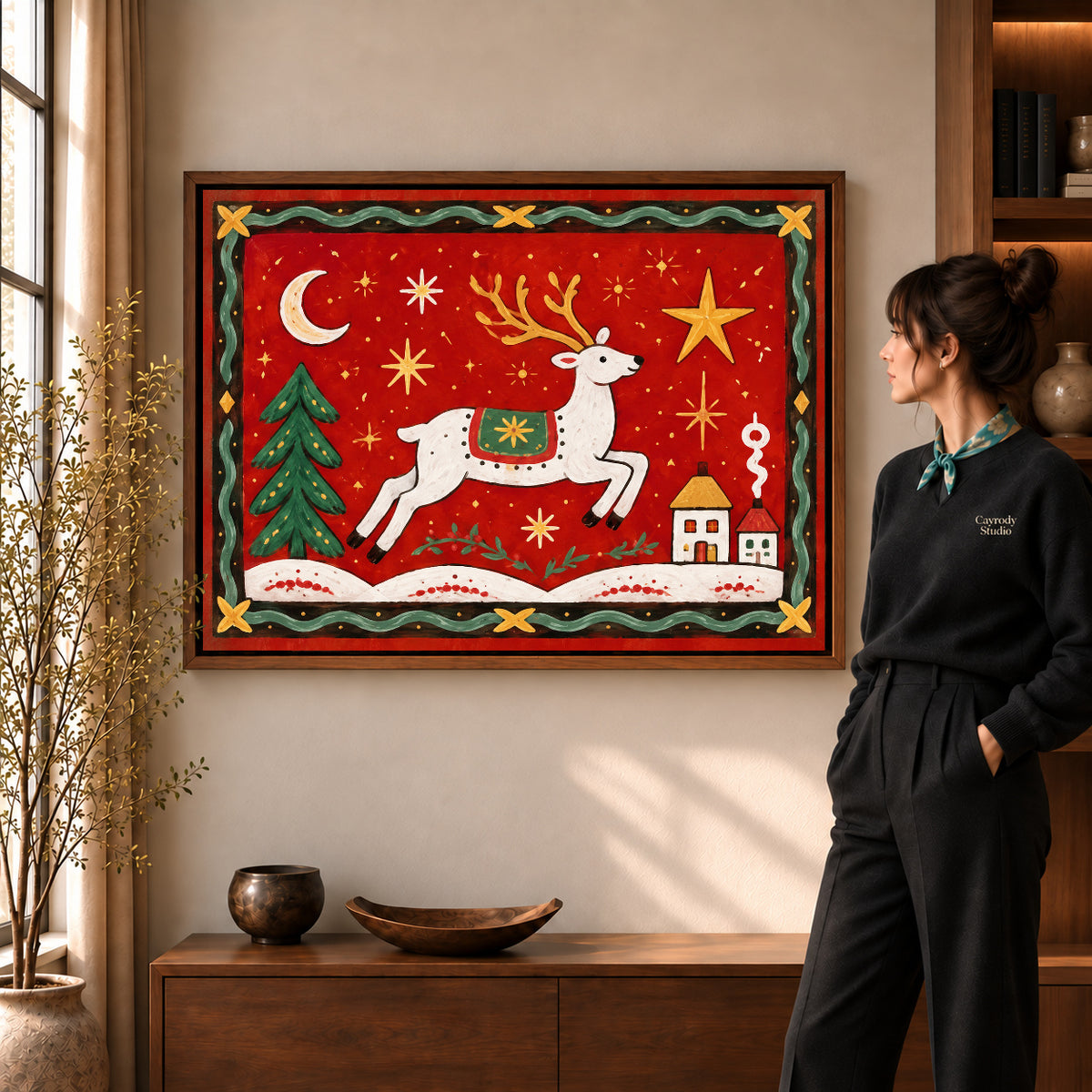 Walnut framed festive folk reindeer canvas art shown beside a standing woman and a wooden console.