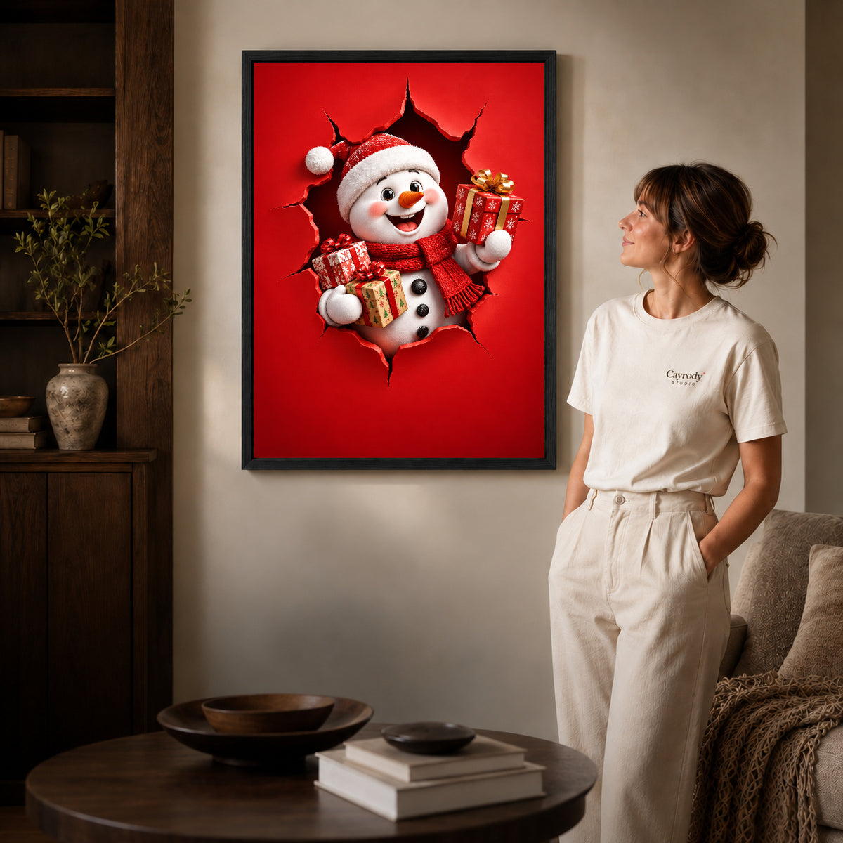 Gift Giving Snowman canvas art in a black frame above books in a welcoming living room.